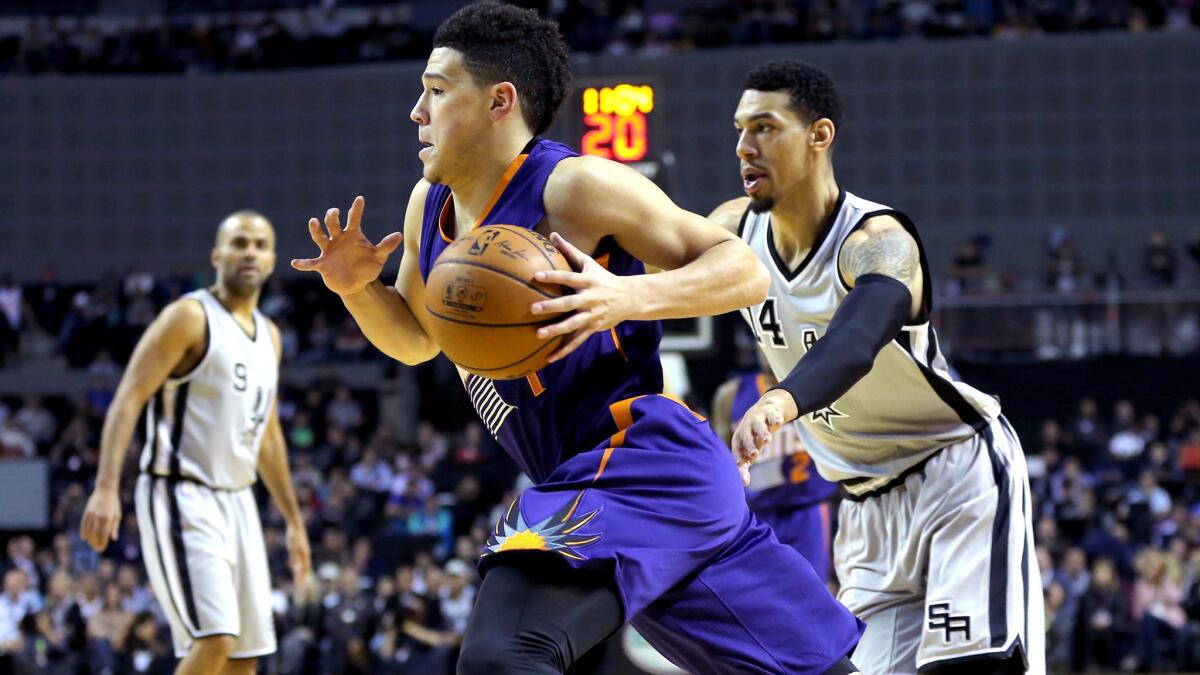 Suns guard Devin Booker drives the baseline against Spurs guard Danny Green during their game Saturday in Mexico City.
