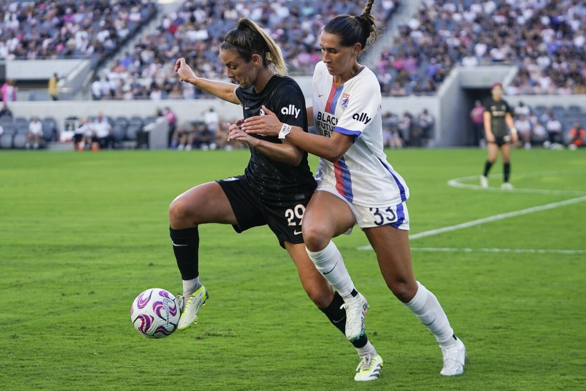 Angel City FC midfielder Clarisse Le Bihan, left, controls the ball in front of OL Reign midfielder Olivia Van der Jagt.