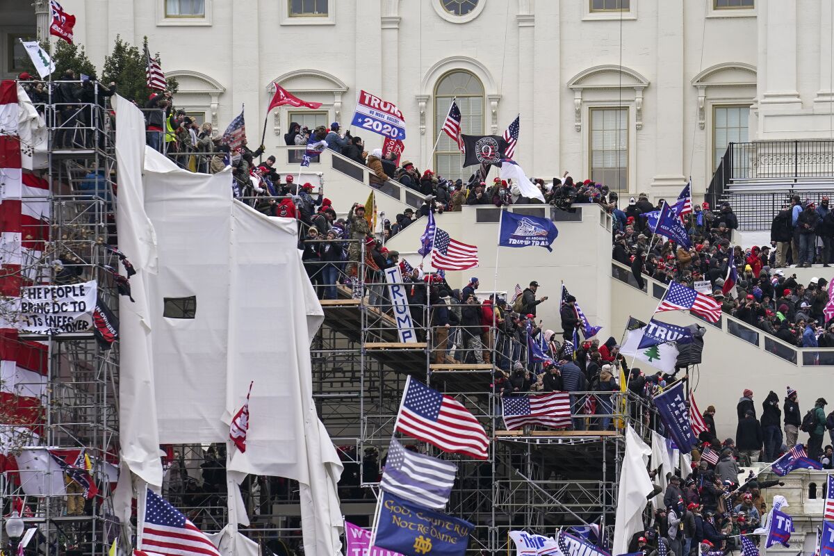 People with flags fill up the stairs outside the U.S. Capitol.