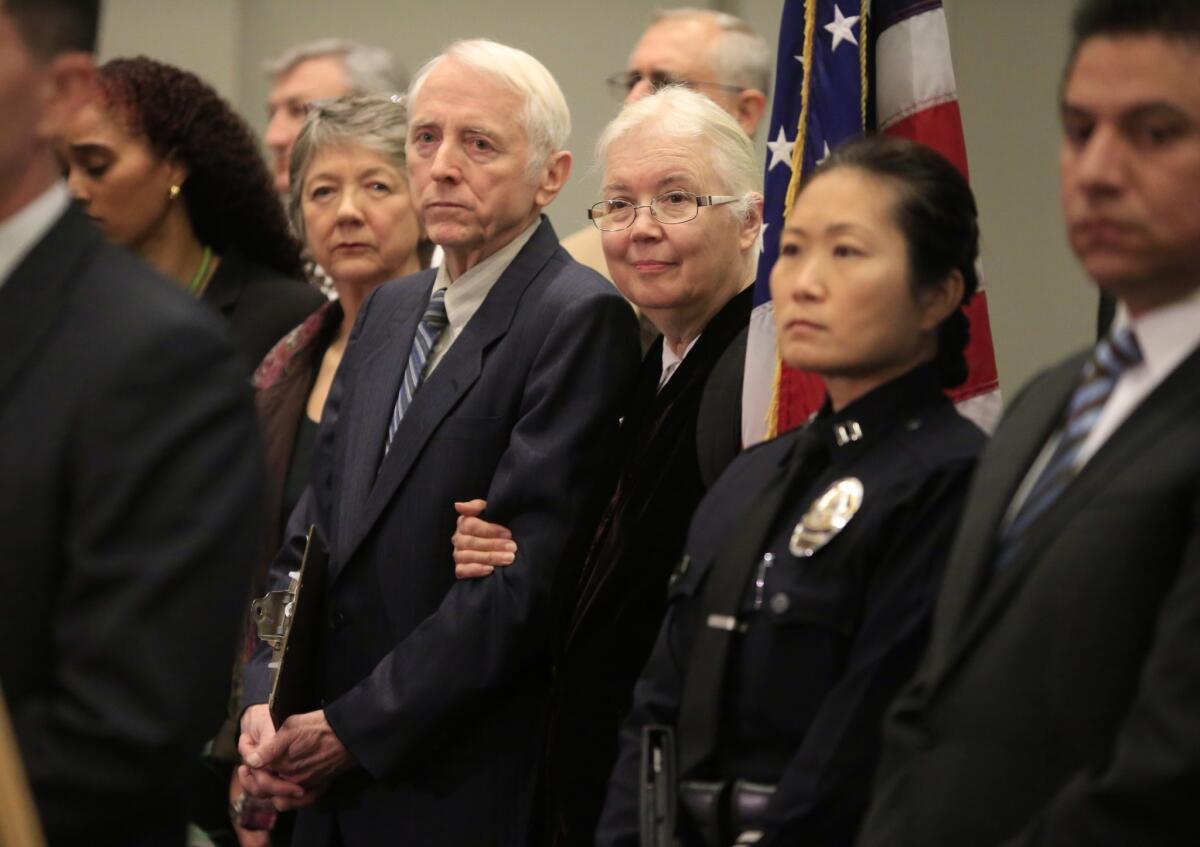 Allan and Jeanne Howe, center, stand together at a press conference at LAPD headquarters to announce a $75,000 reward for information in the murder of their son, television producer James Marcus Howe.