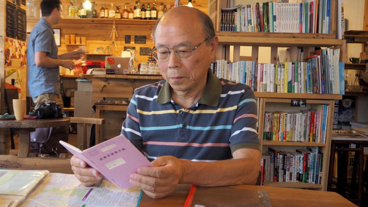 Kazuhiko Futagawa looks at a medical booklet that shows he is entitled to free healthcare, since he is a survivor of the atomic bomb. While his mother never spoke of the horrors of that day, he doesn't want the narrative of the survivors to die with them.