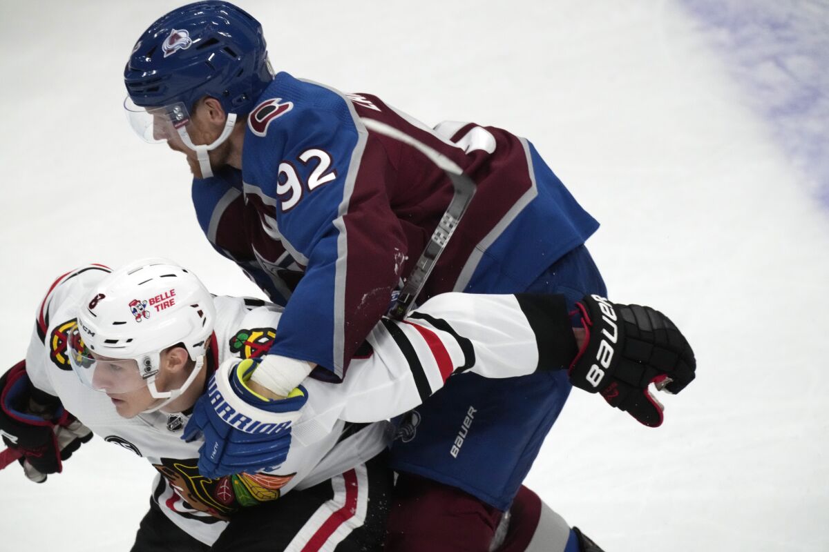 Colorado Avalanche left wing Gabriel Landeskog, top, holds Chicago Blackhawks left wing Dominik Kubalik, and is called for a penalty during the second period of an NHL hockey game Wednesday, Oct. 13, 2021, in Denver. (AP Photo/David Zalubowski)