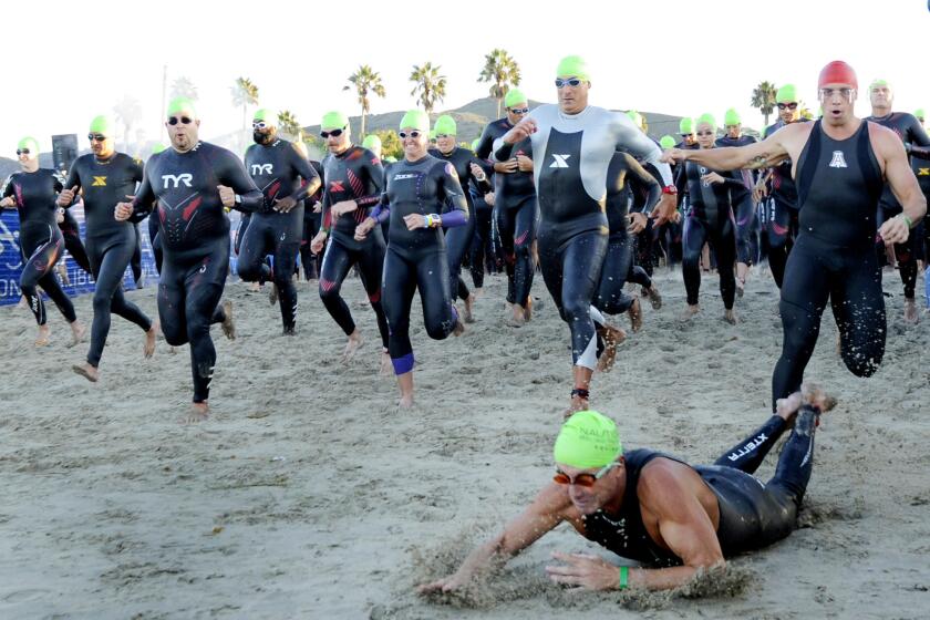 Swimmers make their way down the beach during the start of the Nautica Malibu Triathlon at Zuma beach in Malibu, Calif.