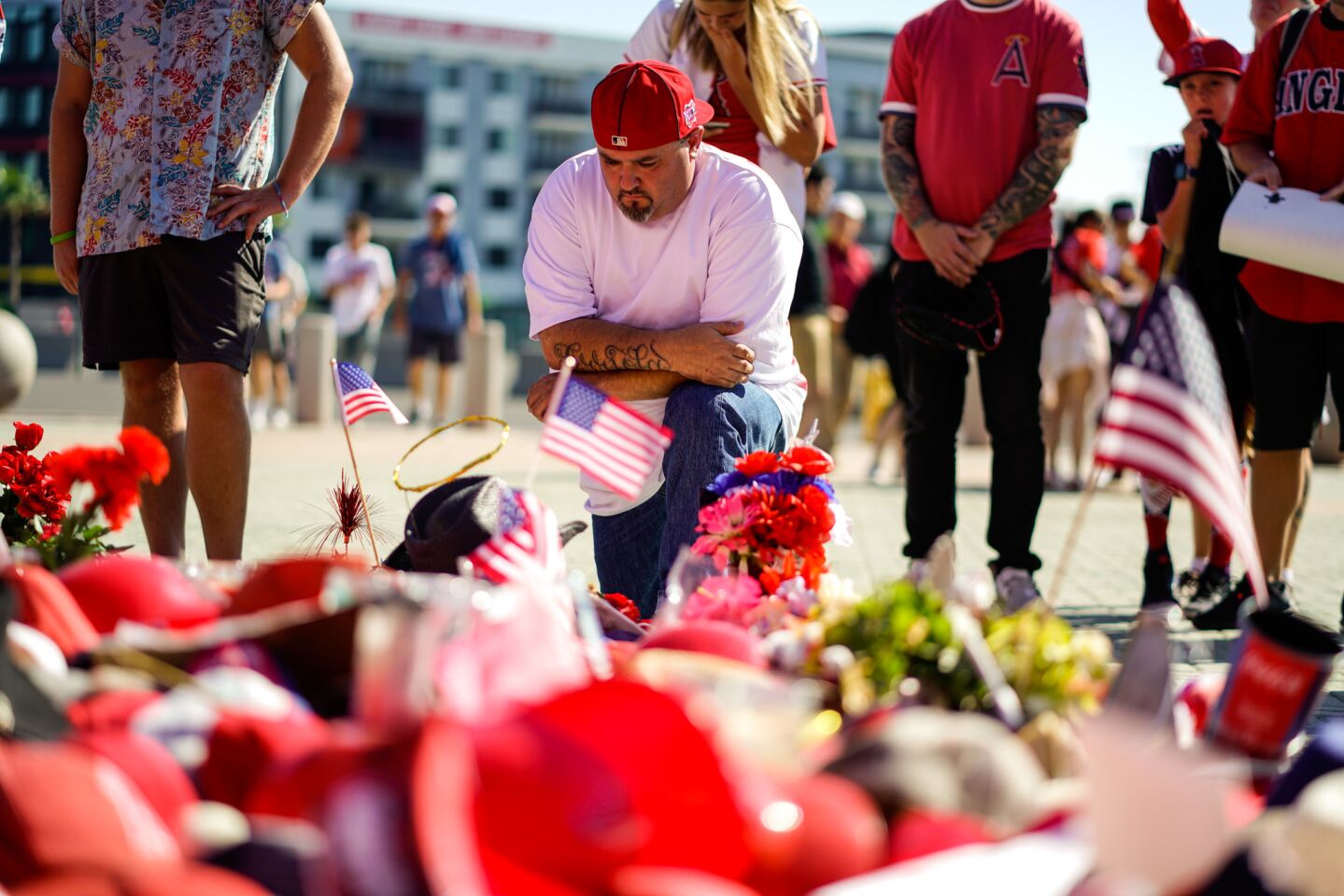 Karl Arriola, 48, of Santa Ana kneels before a memorial for Tyler Skaggs, out in front of Angel Stadium.