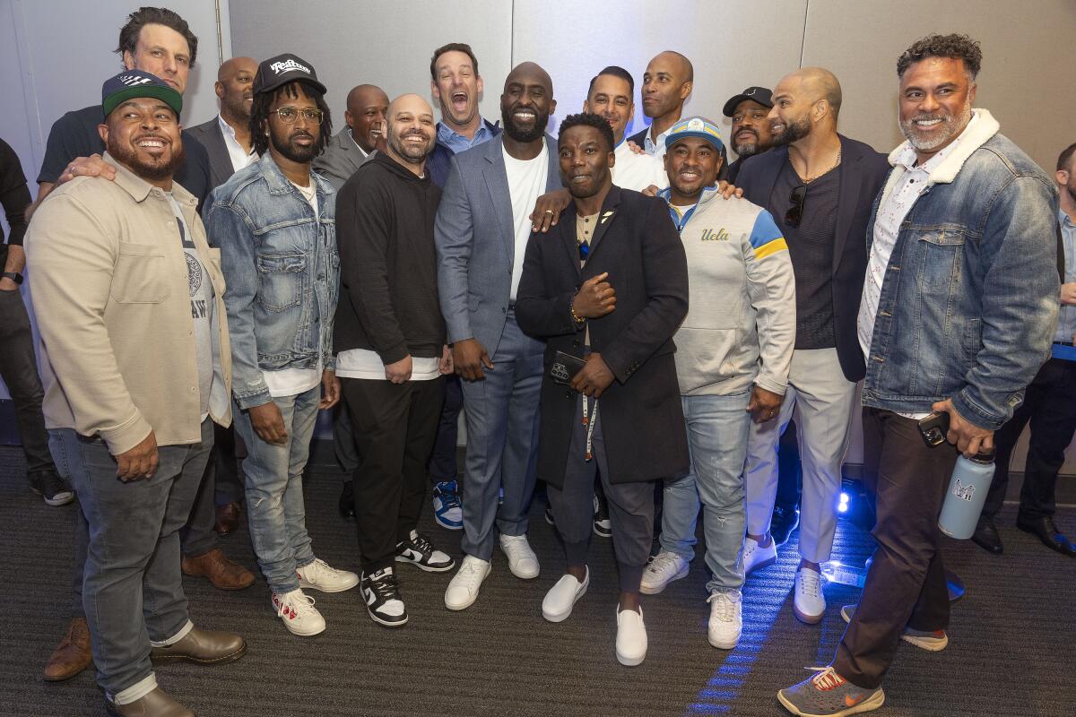 New UCLA football head coach DeShaun Foster takes a group picture with former Bruins football players 