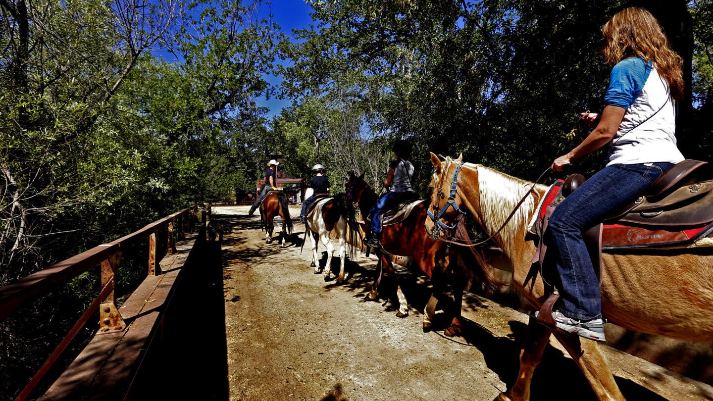 Riders cross a wooden bridge that leads to the Old West town at the site.