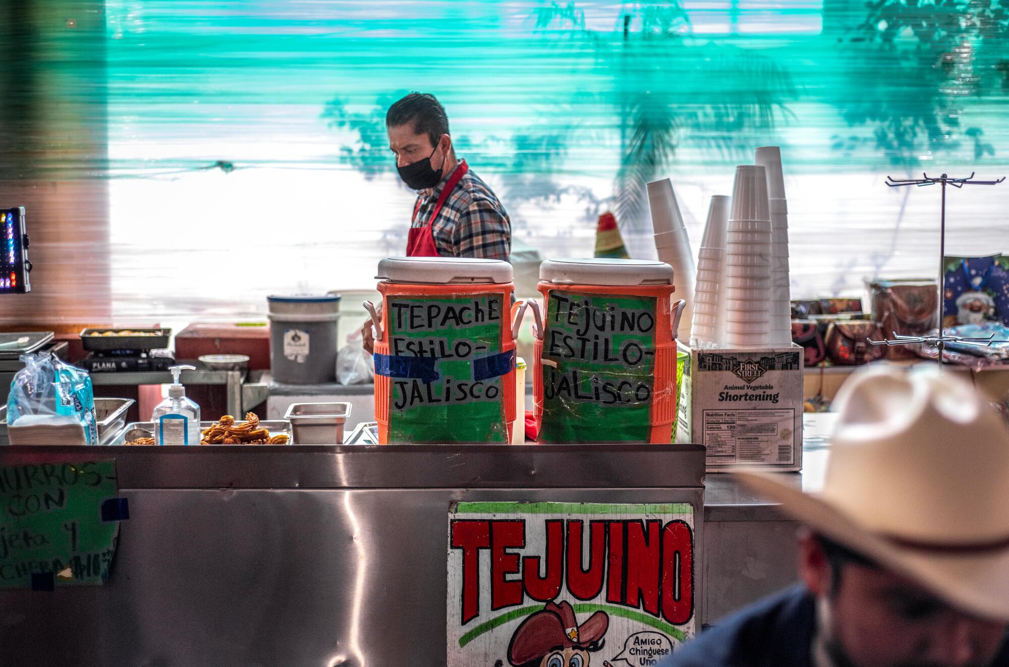A vendor with coolers of tejuino and stacks of styrofoam cups.