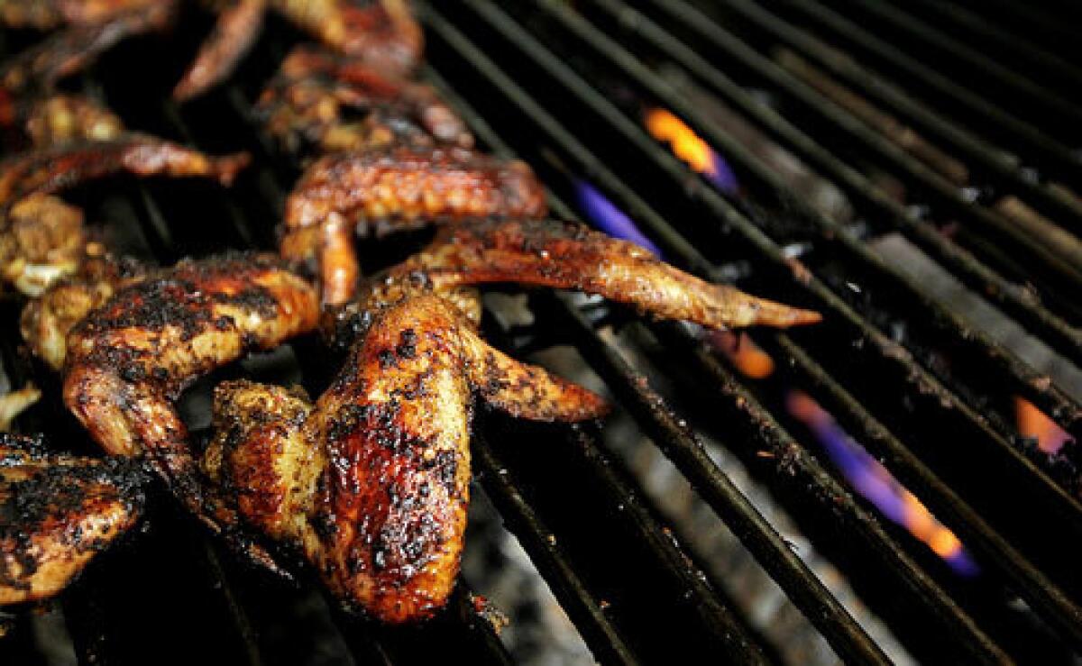 Reggae wings cook on the grill at Front Page Jamaican Grille in Inglewood.
