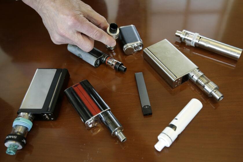 FILE - In this April 10, 2018 file photo, a high school principal displays vaping devices that were confiscated from students in such places as restrooms or hallways at the school in Massachusetts. Schools around the country are installing sensors and cameras to crack down on student vaping, and handing out harsh punishments for many who are caught. Schools have invested millions of dollars in the surveillance technology, including federal COVID-19 emergency relief money meant to help schools through the pandemic. (AP Photo/Steven Senne)