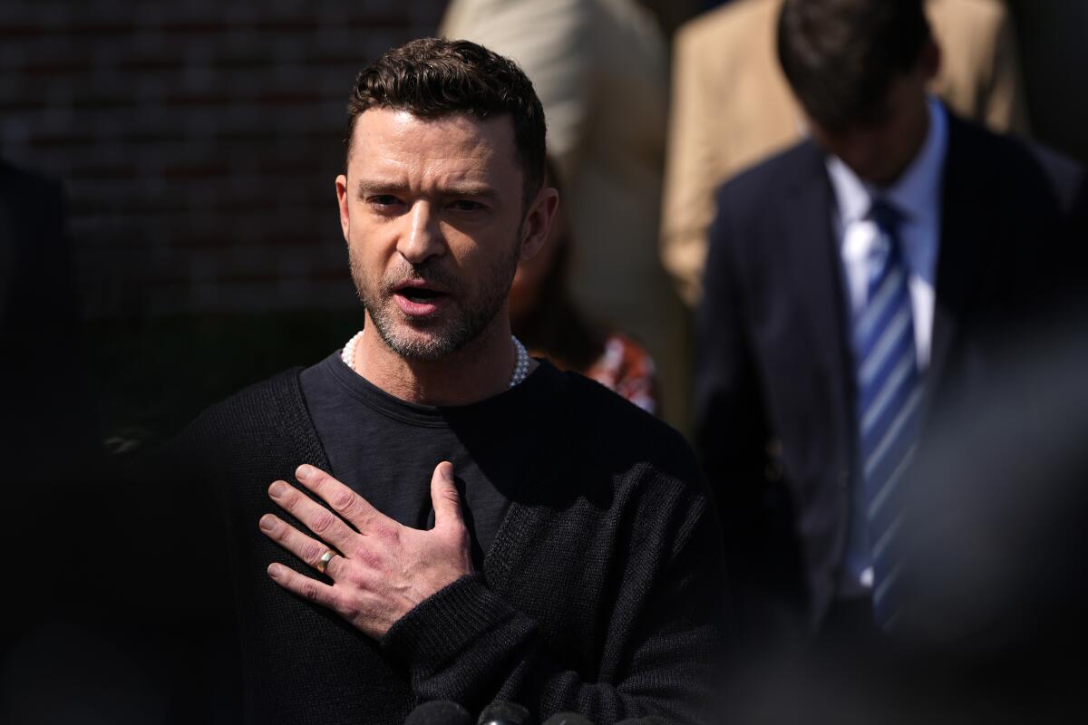 Justin Timberlake puts his open hand to his chest as he speaks outside a courthouse.