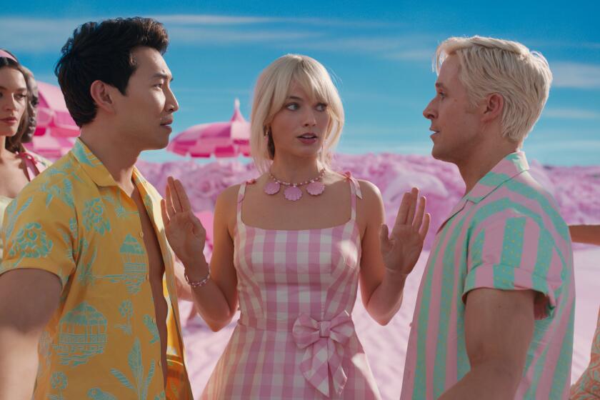 Barbie stands between two Kens staring each other down at a pink beach with another man and woman looking on