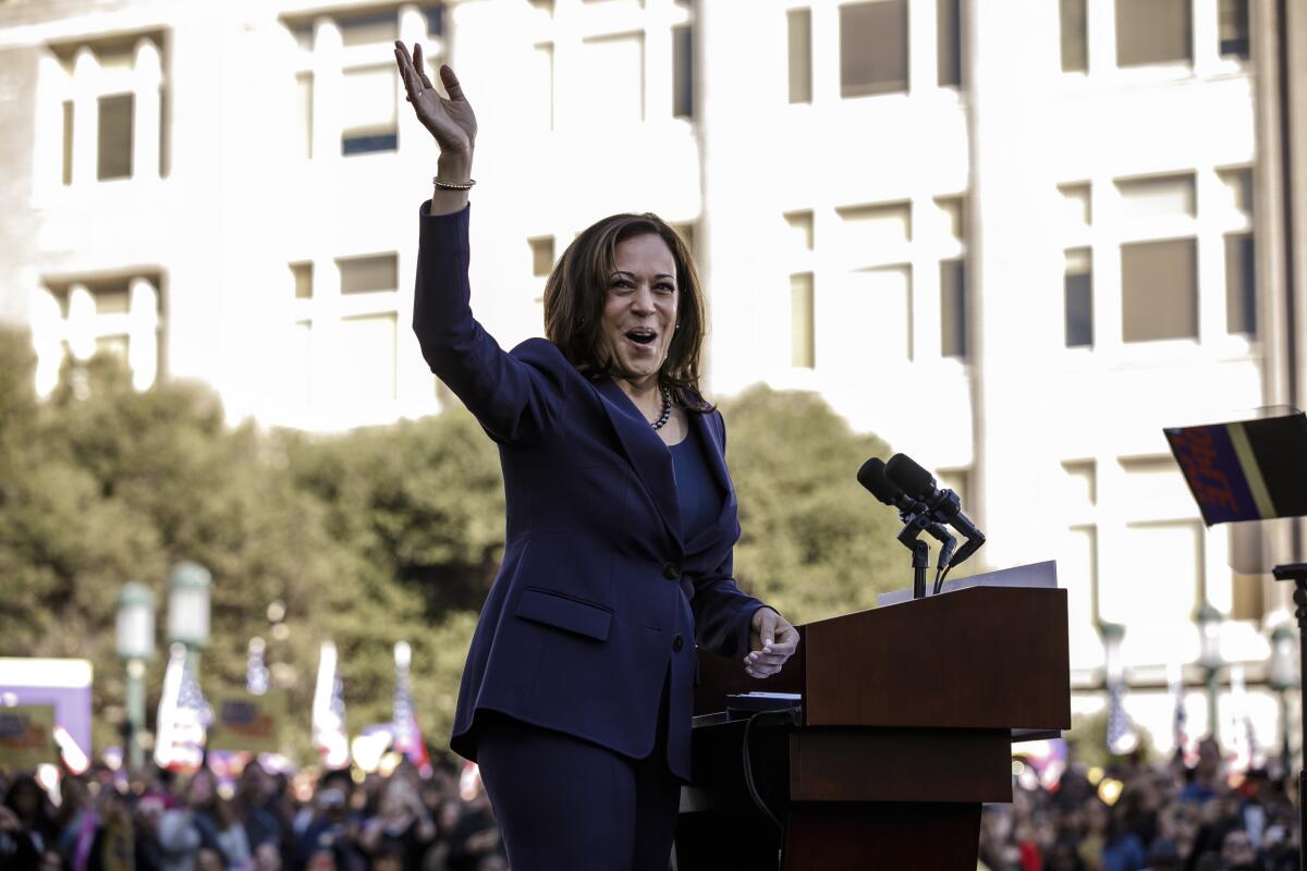 Then-Sen. Kamala Harris waves to a crowd from a lectern 