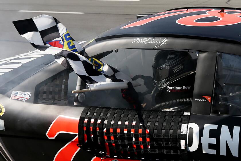 Martin Truex Jr. celebrates with the checkered flag after winning Sunday's NASCAR Sprint Cup Series race at Pocono Raceway on June 7, 2015.