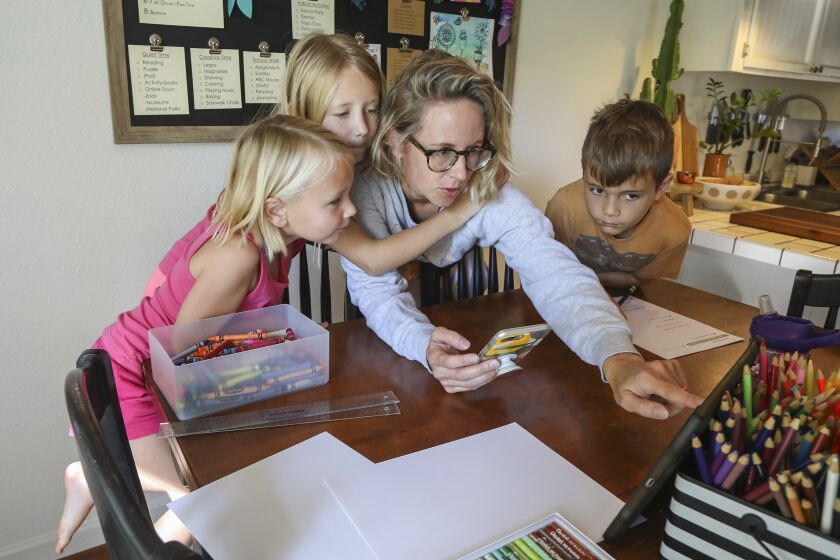 ICU nurse Laura George with her children (from left) Olivia, 5, Lyla, 8, and Jaxon, 9, log onto a Zoom meeting, a Kindergarten thru 2nd grade art class at Parkdale Elementary School, while at home on May 8, 2020 in Encinitas, California. George is an essential worker.
