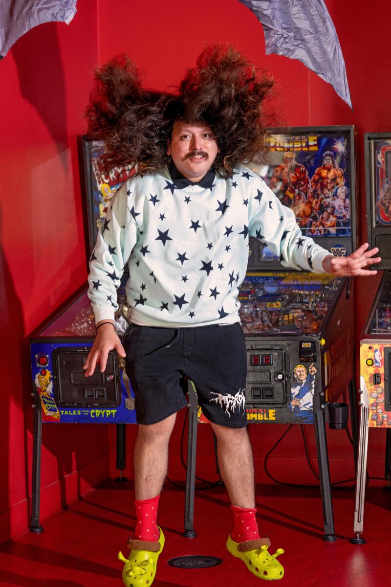 Diego Argoti next to a row of vintage pinball machines at Poltergeist.