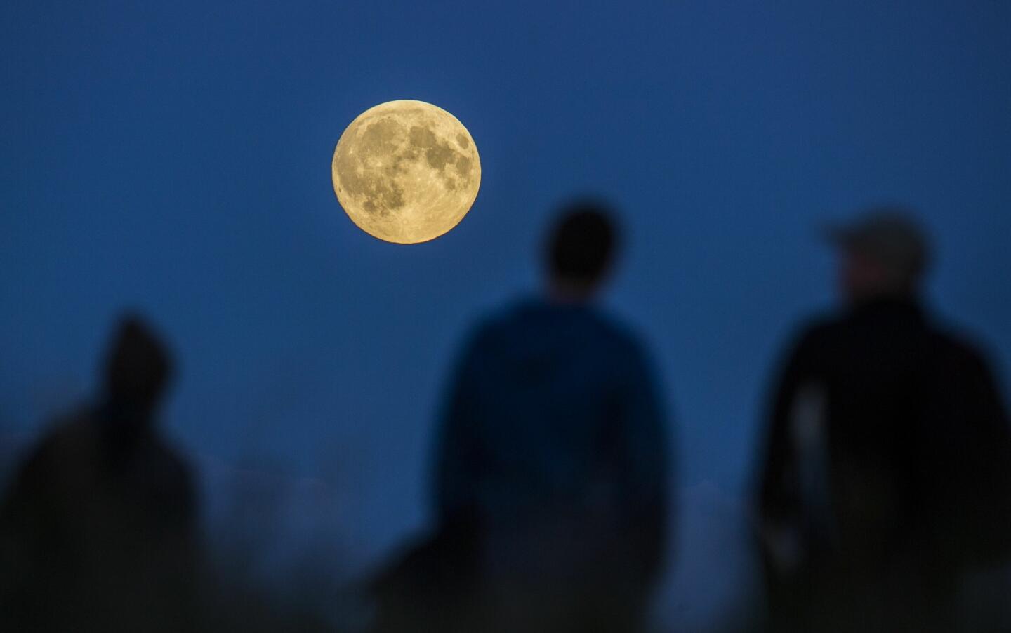 People watch a full moon rising in Berlin, Germany.