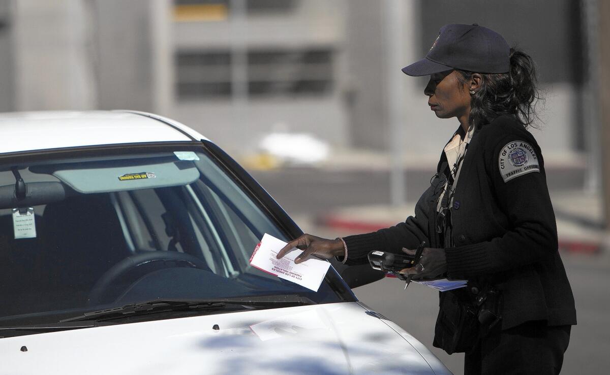 A parking enforcement officer tickets a car parked in an area scheduled for street sweeping.