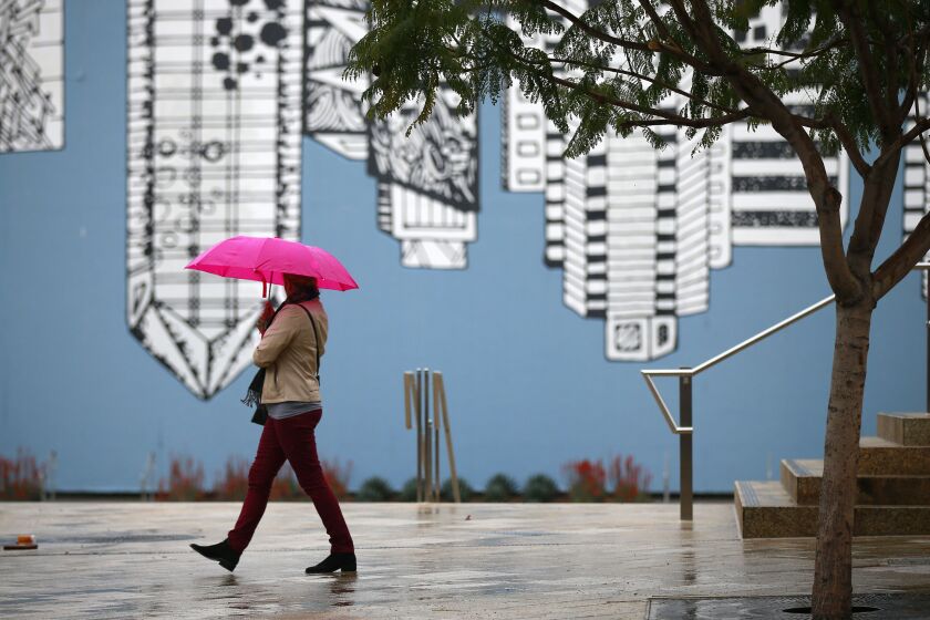 A woman walks in the rain in Horton Plaza Park on March 11, 2019. (Photo by K.C. Alfred/San Diego Union-Tribune)