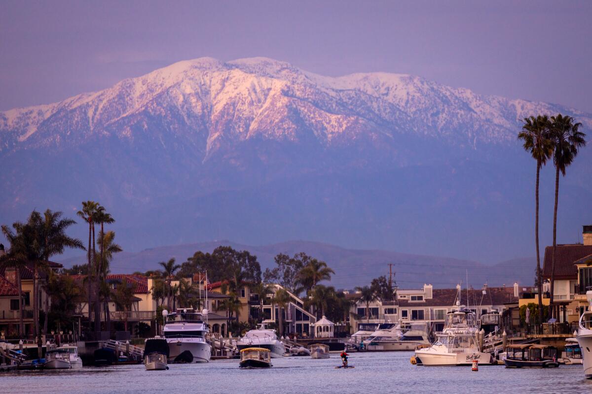 The snowy peaks of mountain range are see from a harbor. 