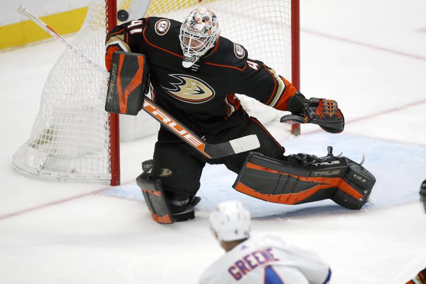 New York Islanders defenseman Andy Greene, bottom, shoots past Anaheim Ducks.