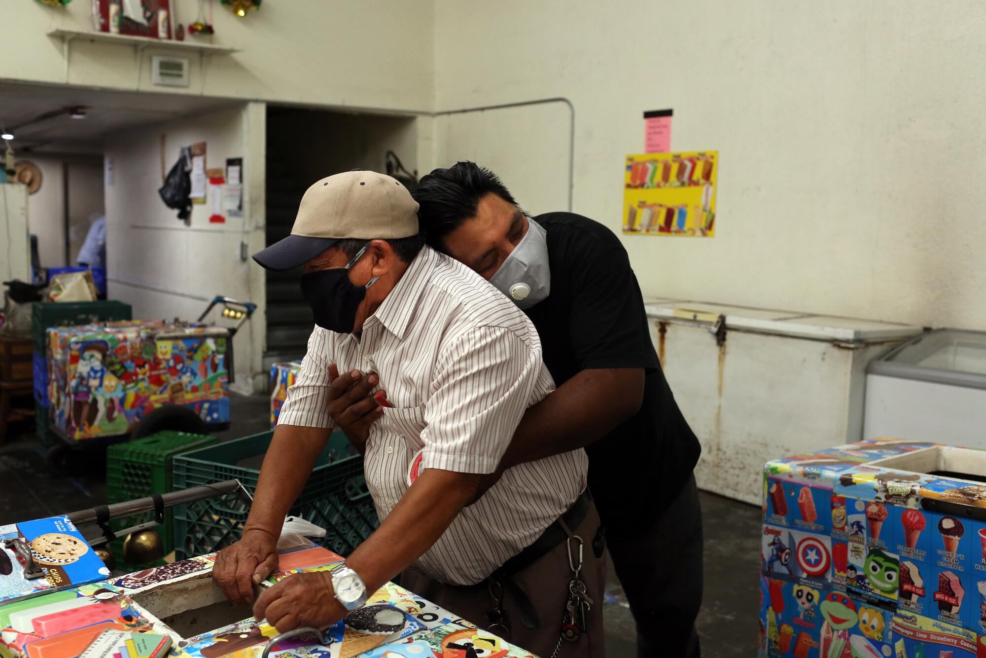 Oscar Samano, right, hugs Rios inside Barahona Ice Cream.