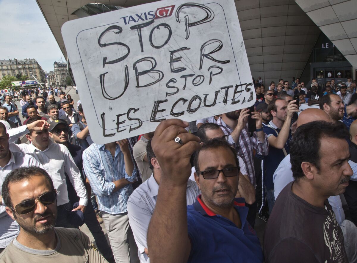 A taxi driver in France holds a placard that reads, "Stop Uber, Stop listening," referring to the new U.S. spying report in France, during a taxi drivers demonstration in Paris.