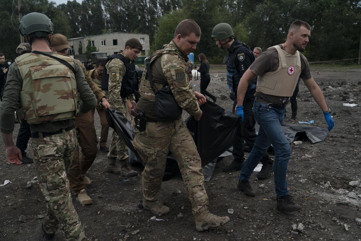 Ukrainian serviceman carry a body in a bag 