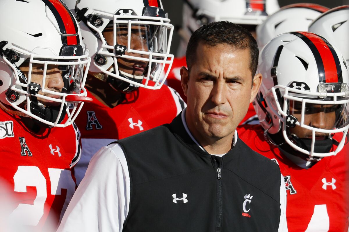 Cincinnati coach Luke Fickell takes the field with his players before a game against Connecticut last season.