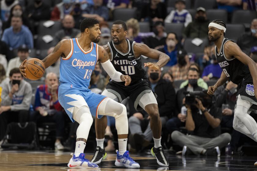 Los Angeles Clippers guard Paul George (13) is defended by Sacramento Kings forward Harrison Barnes (40) during the first quarter of an NBA basketball game in Sacramento, Calif,. Wednesday, Dec. 22, 2021. (AP Photo/José luis Villegas)