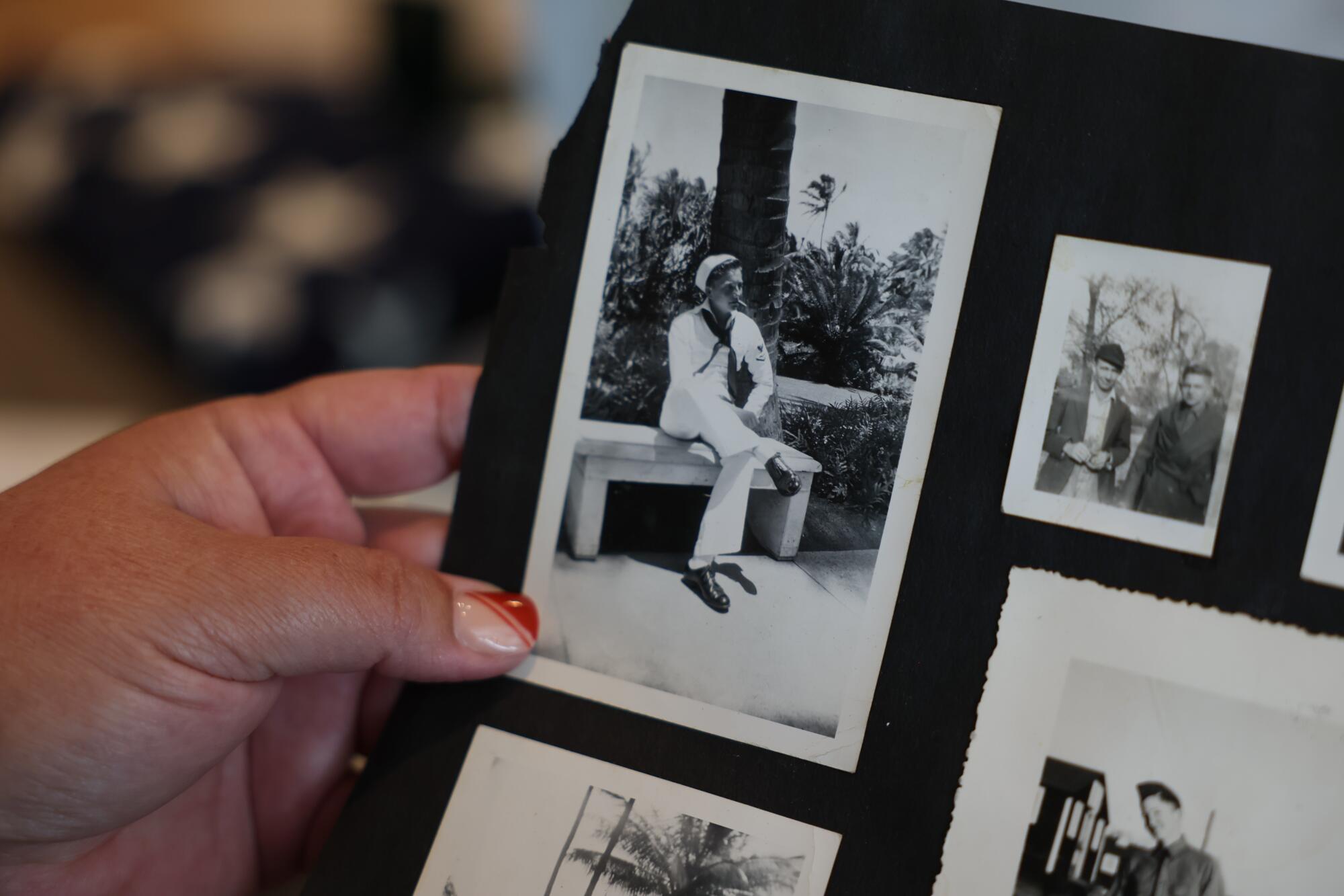 A hand holding photographs on a black page