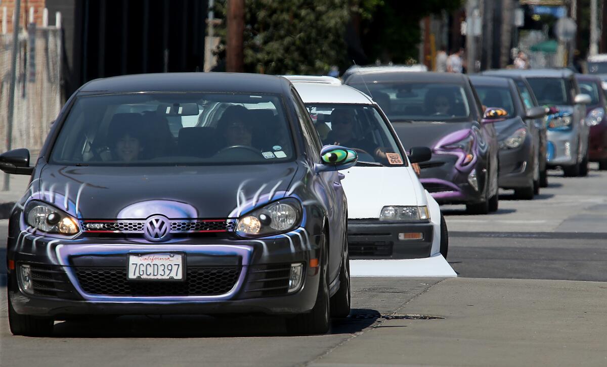A Volkswagen with eyelashes, pupils and a mouth grill joins a caravan of Kenny Scharf's Karbombz!