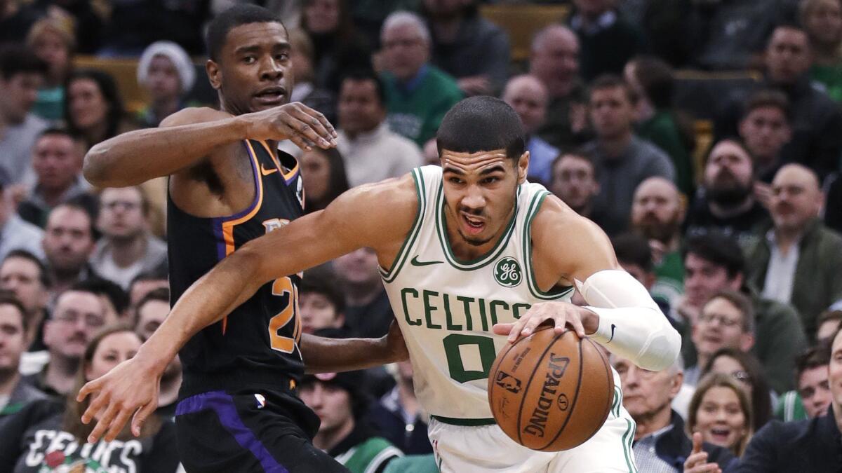 Boston Celtics forward Jayson Tatum (0) drives to the basket past Phoenix Suns forward Josh Jackson, left, during the first quarter.