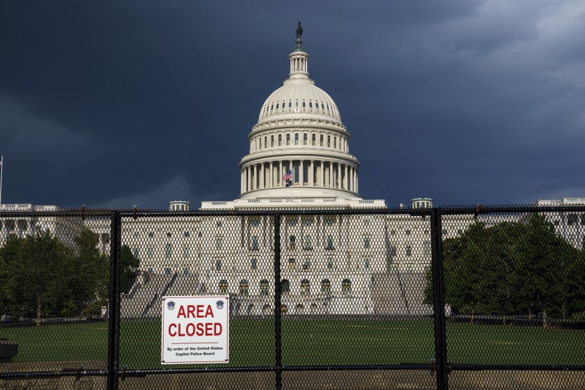 The U.S. Capitol is seen under dark skies in Washington, Tuesday, June 8, 2021, as barriers remain six months after the Jan. 6 attack. A Senate report examining security failures surrounding the Jan. 6 insurrection at the U.S. Capitol blames missed intelligence, poor planning and multiple layers of bureaucracy for the deadly siege. (AP Photo/J. Scott Applewhite)