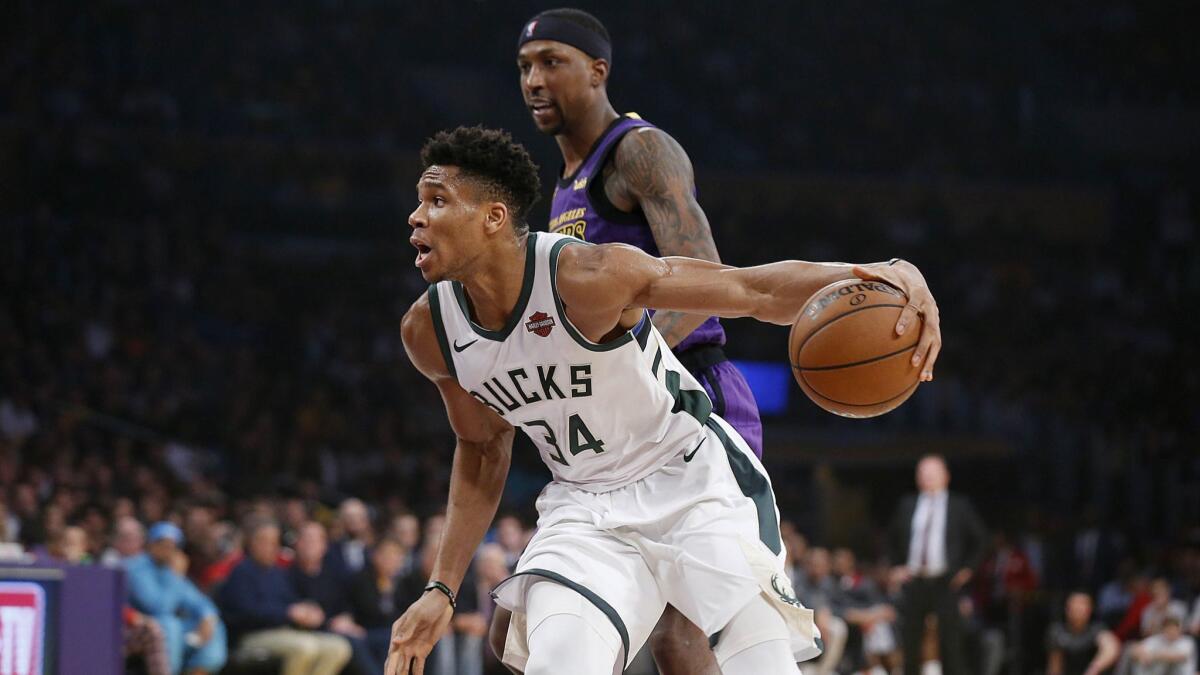 Milwaukee Bucks' Giannis Antetokounmpo (34) dribbles around Lakers' Kentavious Caldwell-Pope (1) in the first half at the Staples Center.