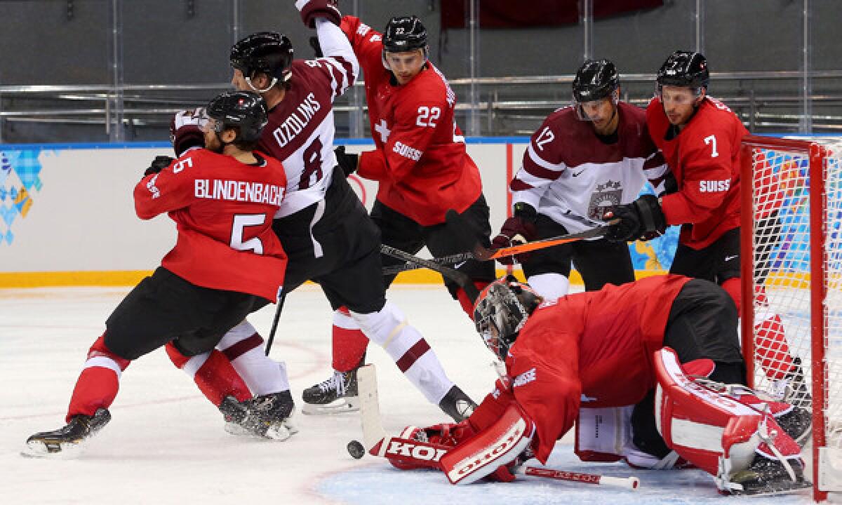 Switzerland goalie Jonas Hiller, bottom right, makes a save during a 1-0 win over Latvia on Wednesday.