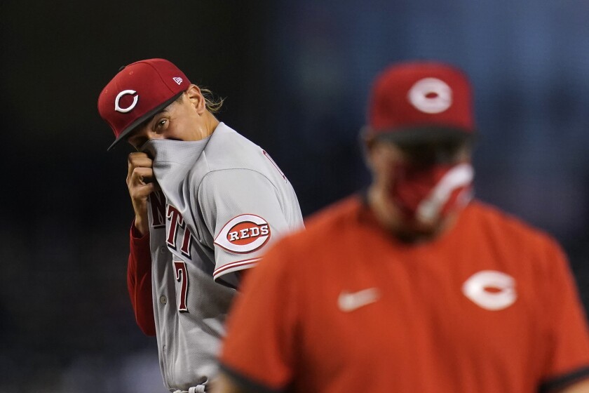 Cincinnati Reds starting pitcher Jose De Leon, left, wipes sweat from his face after getting a visit from Reds pitching coach Derek Johnson, right, as a result of giving up a three-run home run to Arizona Diamondbacks' David Peralta and during the third inning of a baseball game Sunday, April 11, 2021, in Phoenix. (AP Photo/Ross D. Franklin)