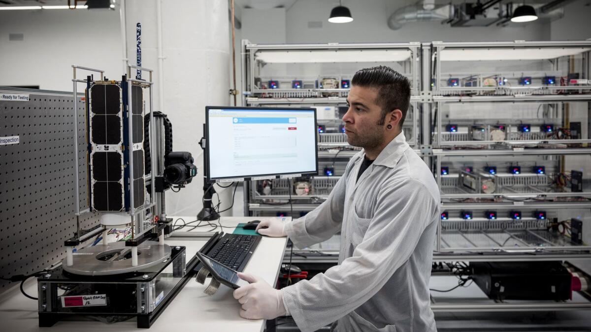 Technician Raul Perez runs tests on a satellite at the manufacturing and testing facilities of Planet, a San Francisco-based company that makes bread-loaf-sized satellites.