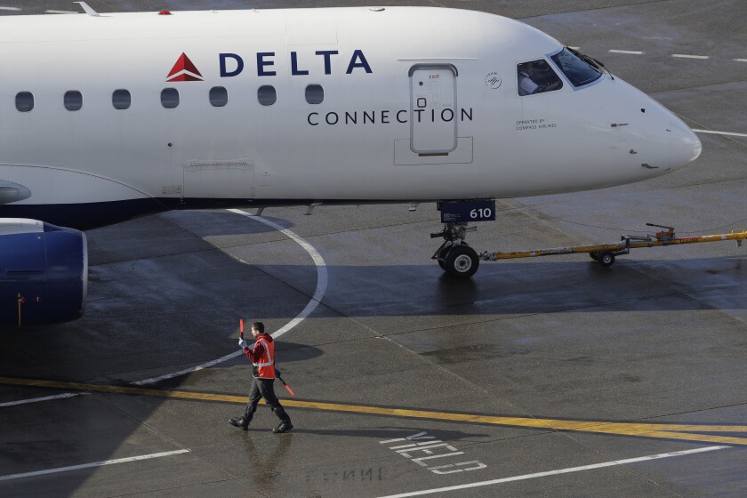 FIE - In this Feb. 5, 2019, file photo a ramp worker guides a Delta Air Lines plane at Seattle-Tacoma International Airport in Seattle. Delta Air Lines says it earned $1.1 billion in the fourth quarter by operating more flights and filling a higher percentage of seats. The financial results beat Wall Street expectations. Delta and other U.S. airlines are enjoying a prolonged period of profitability thanks to steadily rising demand for travel. (AP Photo/Ted S. Warren, File)