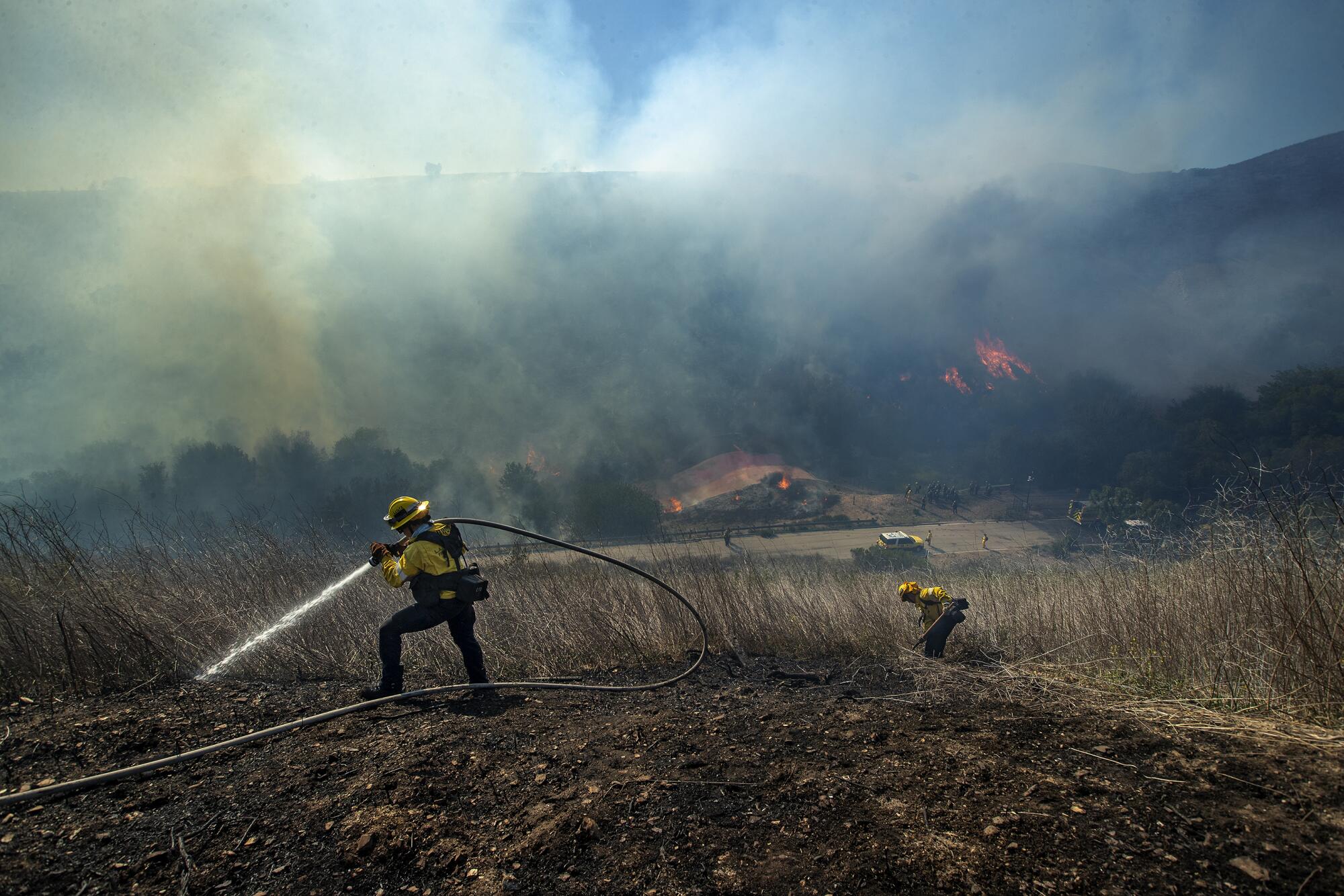 Los Angeles County firefighters Jordan Murren, left, and Tim Luna extinguish a hot spot during the Country fire.