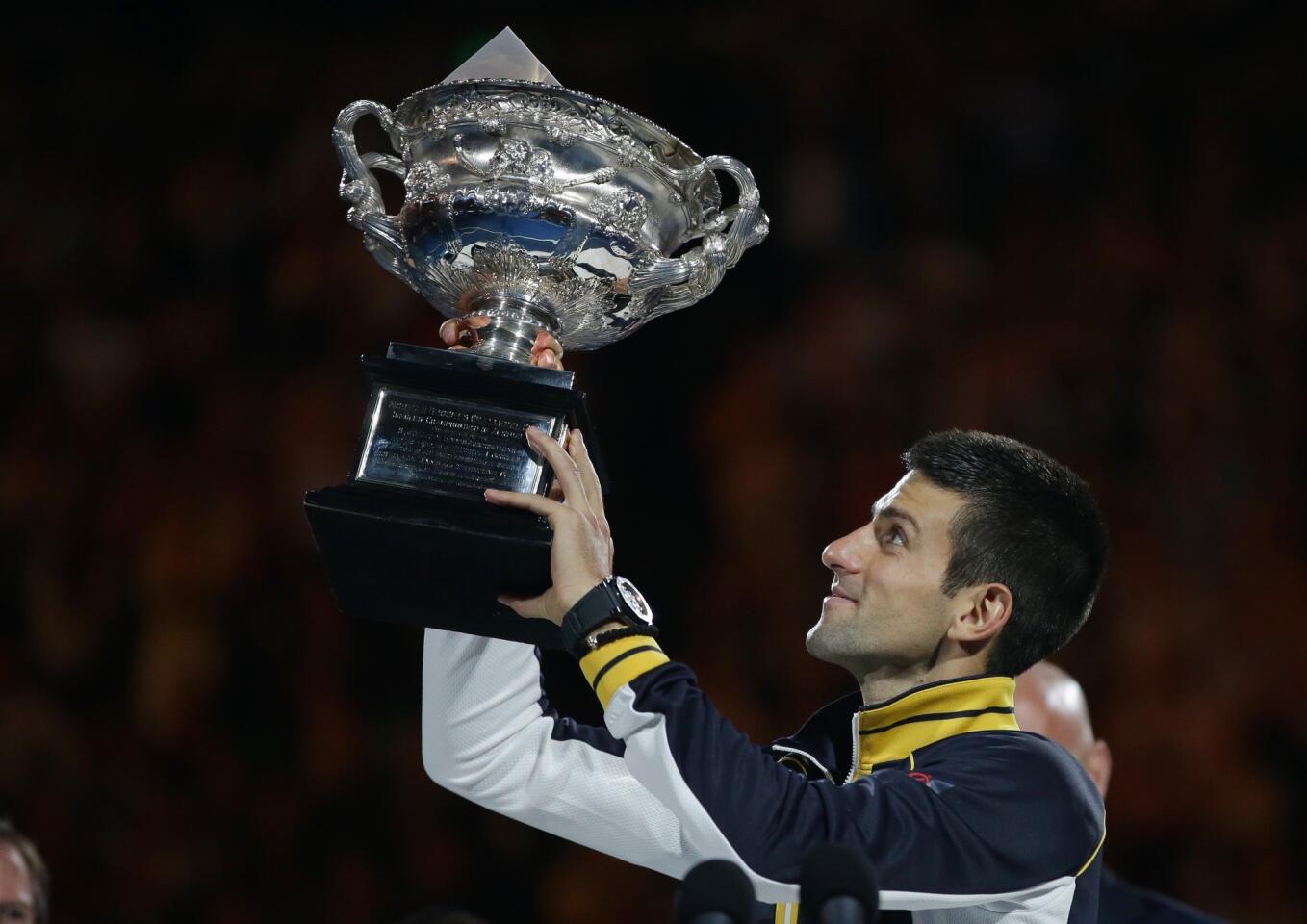 Novak Djokovic becomes the first player in the Open era to hold aloft the Australian Open trophy for the third consecutive year.