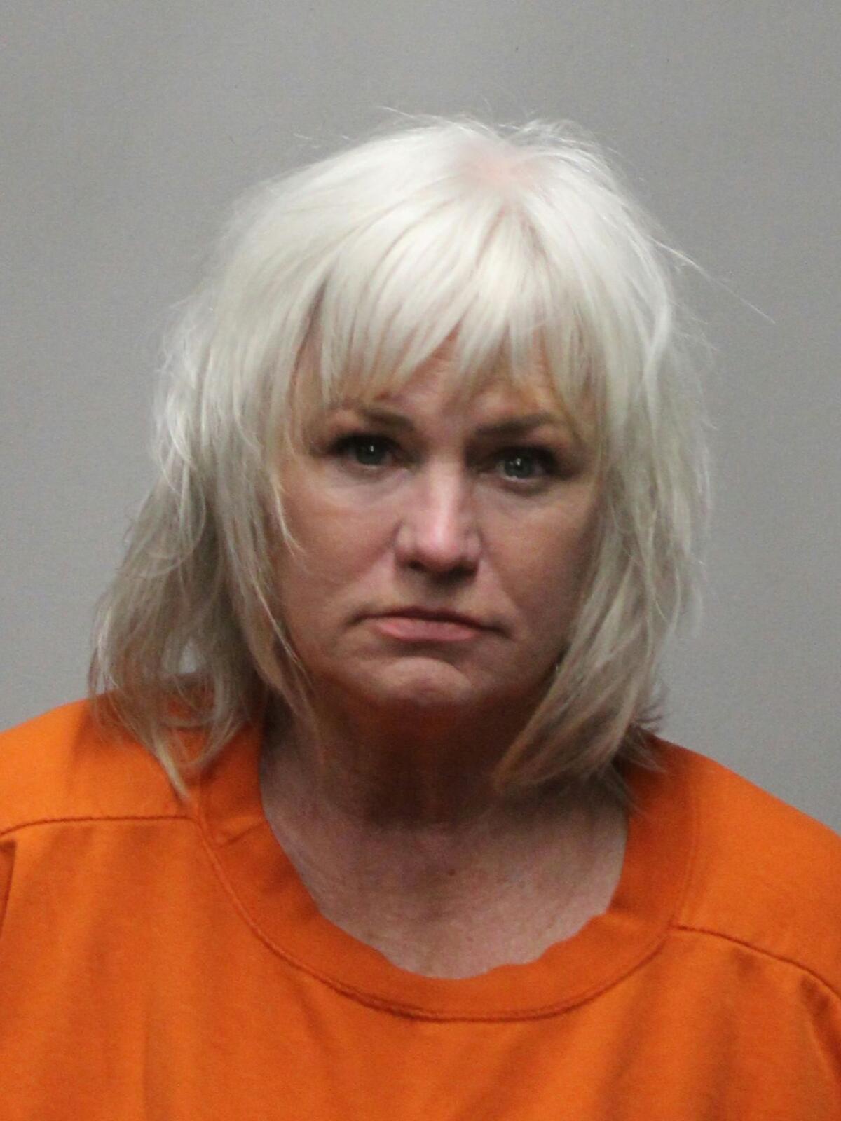 Wendy Munson wearing an orange crewneck shirt in a police booking mugshot