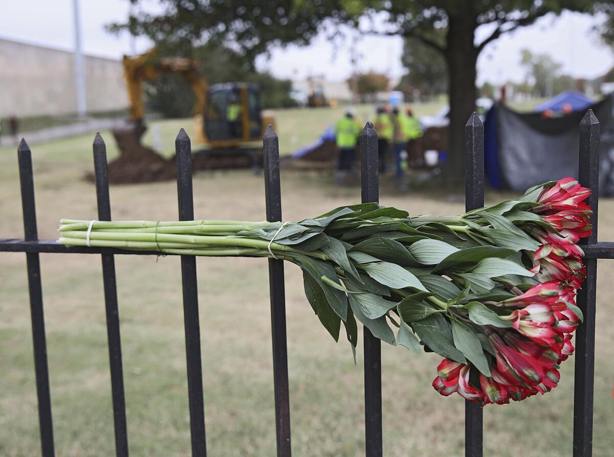 Flowers left by a mourner hang on a fence at Oaklawn Cemetery 