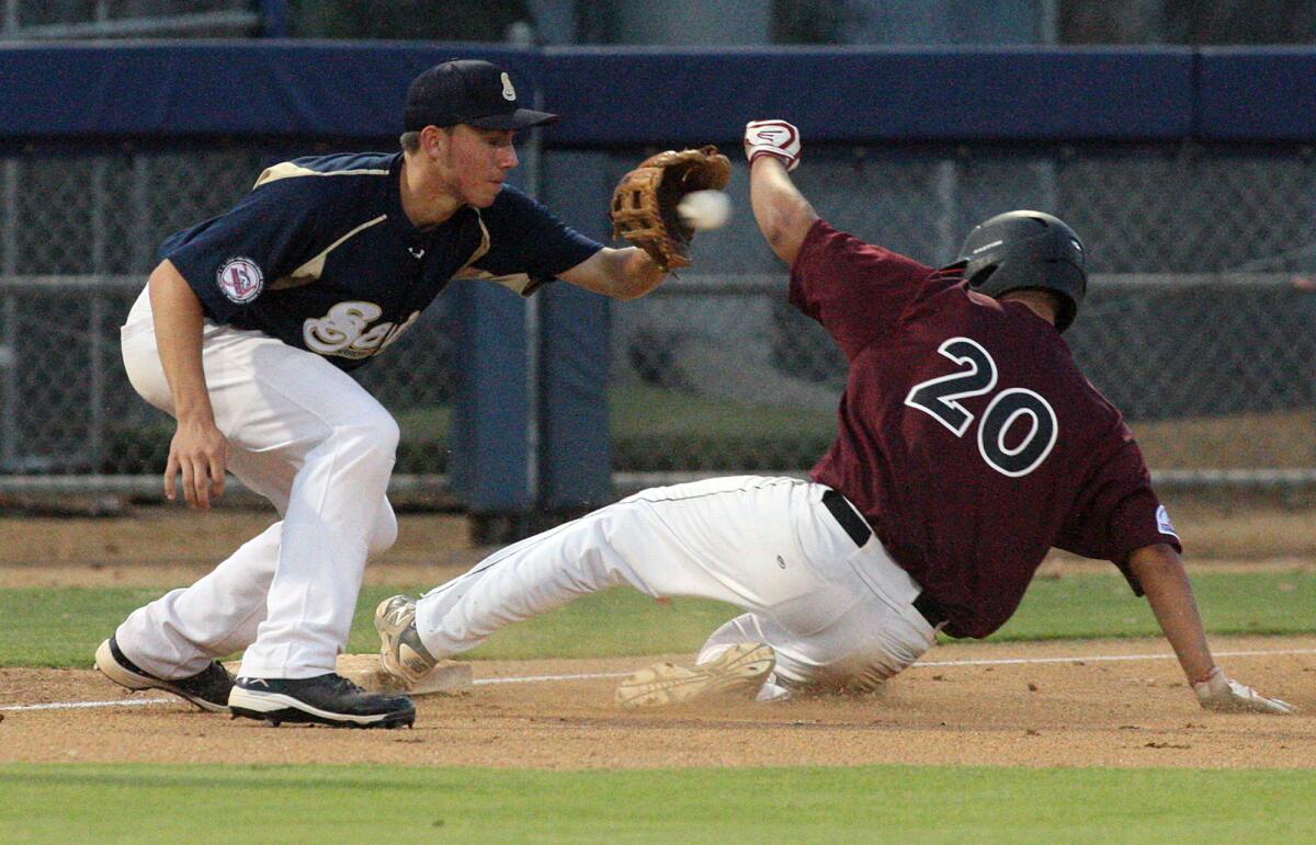 Arroyo Seco Saints' Frankie Garriola catches the ball that arrives a little late to third base as Urban Youth Academy's Richard Samundo slides in safely in the championship game of the Palomino West Zone in Compton on Tuesday, July 29, 2014.