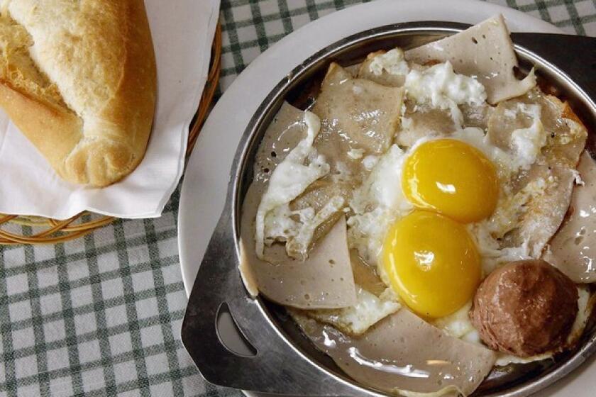 Sunny-side-up eggs with pâté and ham are served with a baguette at Uyen Thy in Westminster.