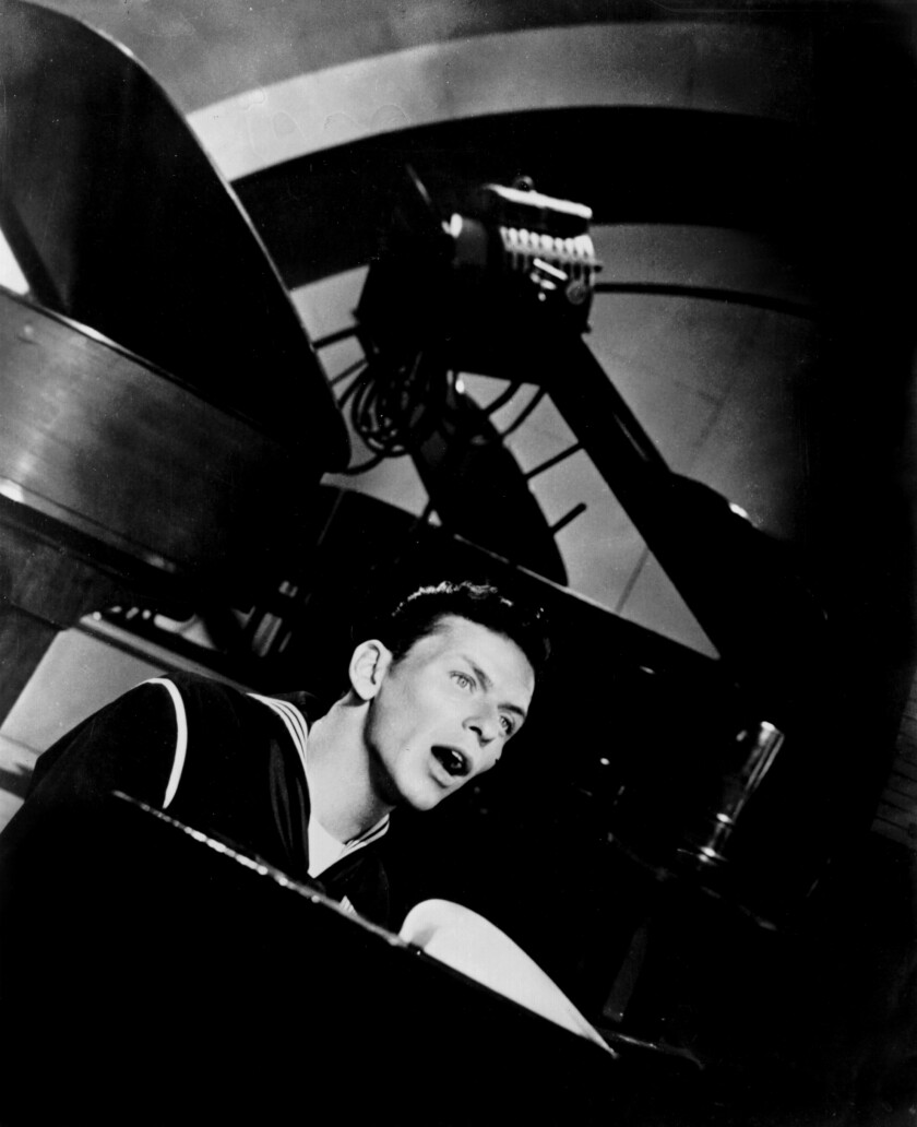 Frank Sinatra plays piano onstage in a scene from  "Anchors Aweigh."