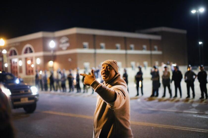 Police face off with demonstrators outside the police station in Ferguson, Mo.