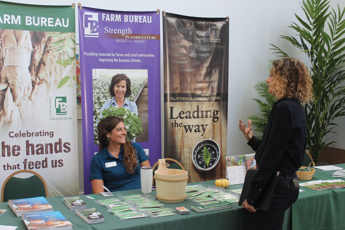 An attendee talks to a woman at an information booth at a previous San Diego Farm & Nursery Expo.