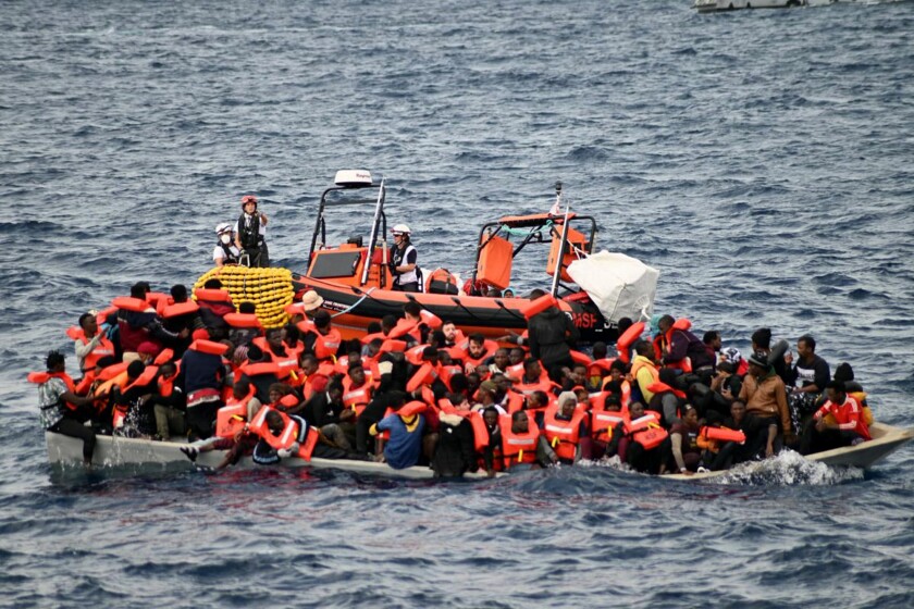 In this photo released by Doctors Without Borders, an overcrowded wooden boat packed with 99 migrants is approached by a tender of the humanitarian organization off the Libya coast on Tuesday, Nov. 16, 2021. Ten people were found dead at the bottom of the boat rescued by a ship operated by Doctors Without Borders, the aid group said. (Candida Lobes/MSF via AP)