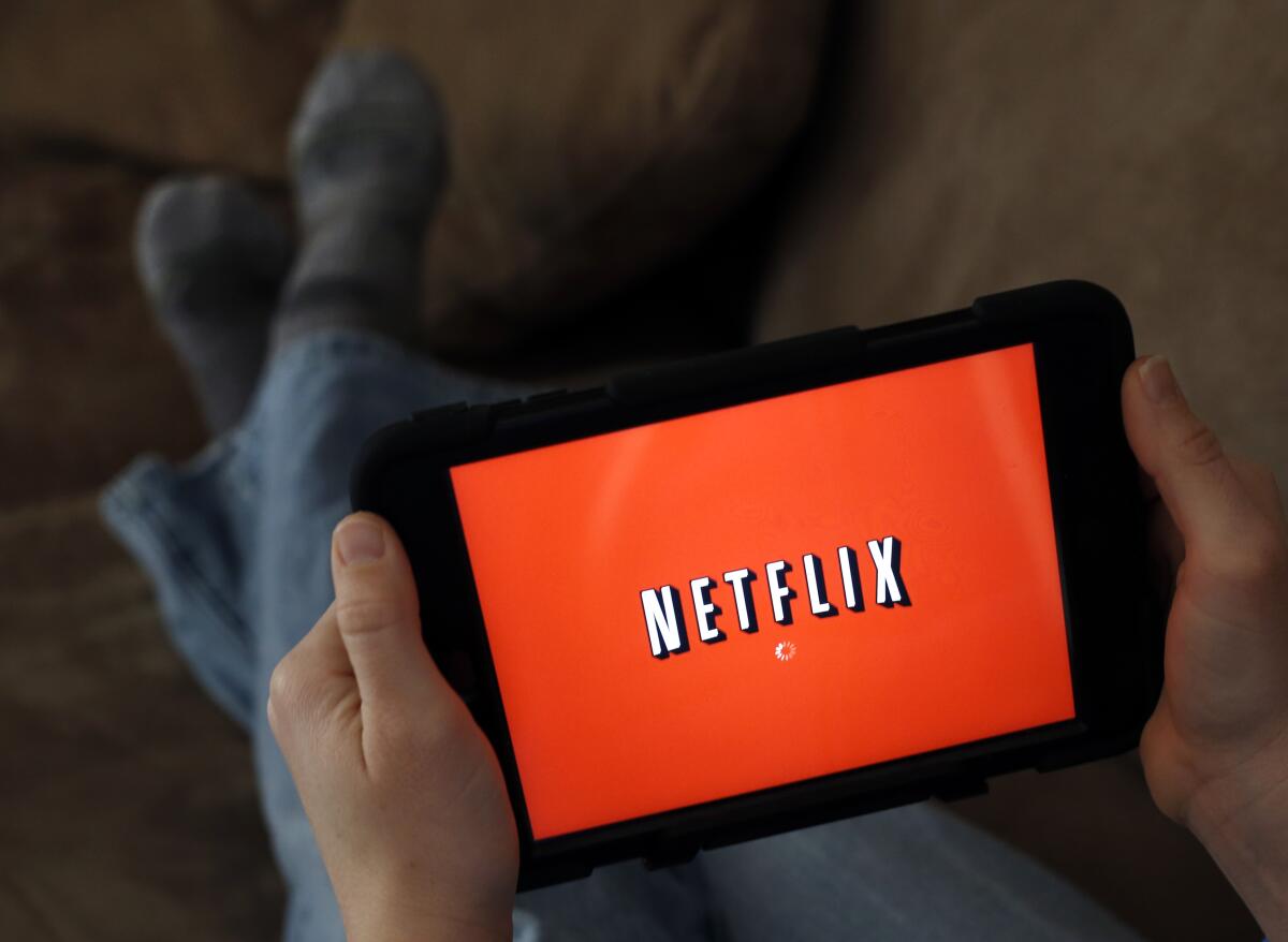 A person displays Netflix on a tablet. 