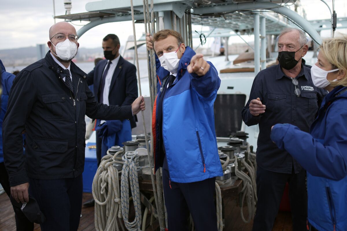 European Council President Charles Michel, left, listen to French President Emmanuel Macron on board of the 7th Continent expedition sailing ship to go admire the Calanques National Park, a marine reserve known for its azure blue waters overhung by high white cliffs, near Marseille, southern France, Friday Sept. 3, 2021. Macron is expected to urge the world to better protect biodiversity as key to fight climate change and support human welfare at a global summit starting Friday in southern France. (AP Photo/Daniel Cole, pool)